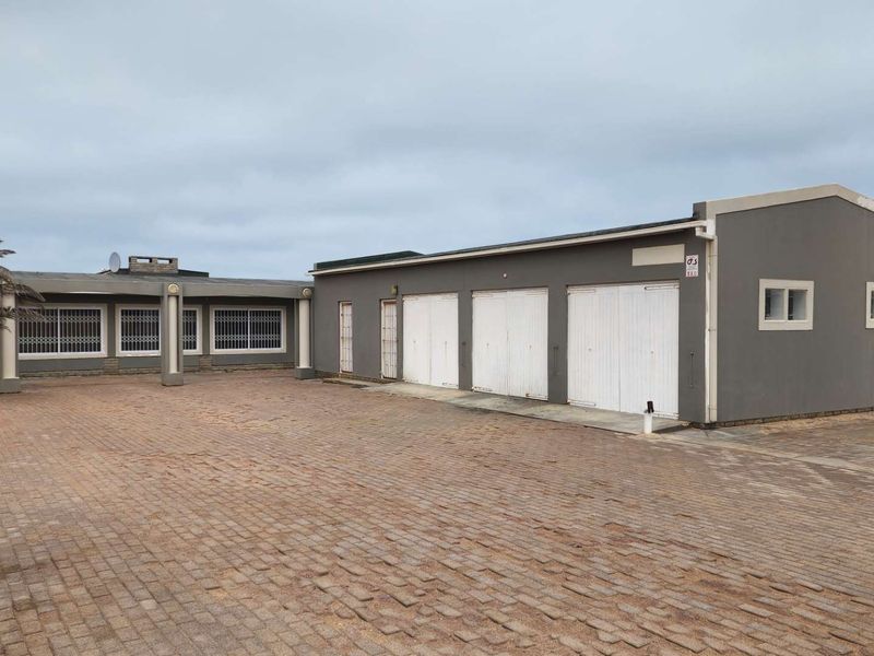 Front exterior view of the property featuring a large paved driveway and a triple garage with security doors.