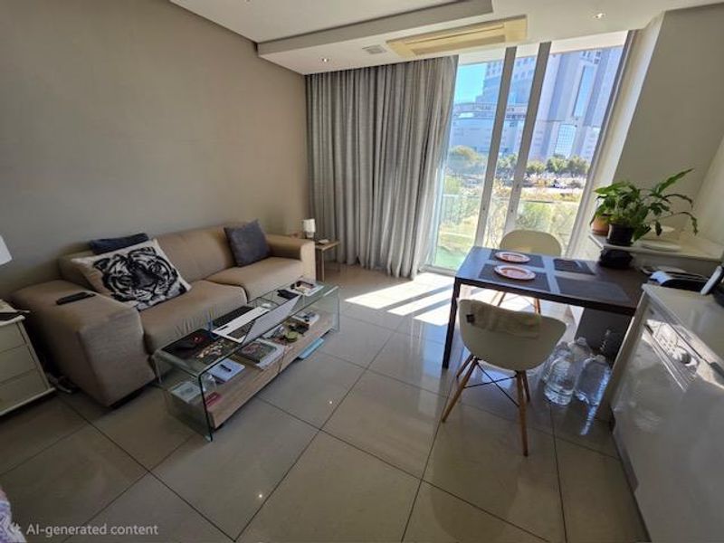 Modern open-plan living and dining area featuring large format floor tiles, recessed ceiling lighting, and floor-to-ceiling sliding doors leading to a balcony.