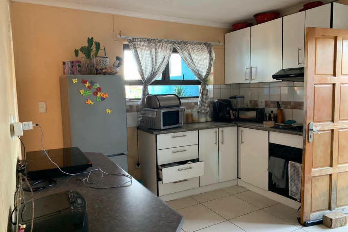 A functional kitchen featuring white cabinetry, laminate countertops, tiled flooring, and a tiled backsplash, offering potential for modernization and cosmetic updates.