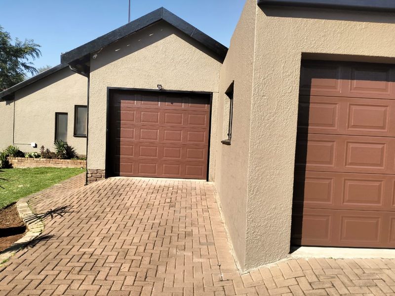 Front view of the property featuring a paved driveway and two garage doors with a neutral stucco finish.