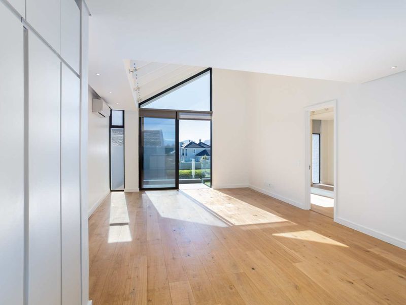 Bright and spacious living area featuring light timber flooring, a vaulted ceiling, and large sliding glass doors leading to an outdoor space.