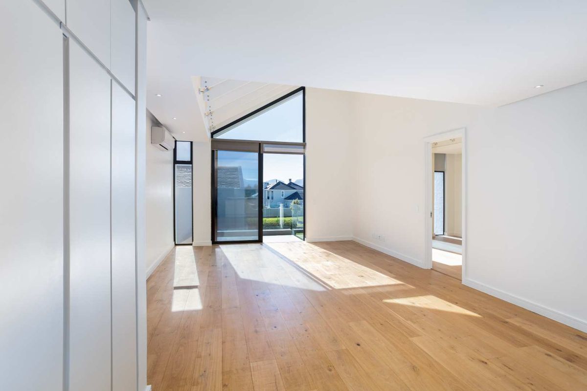 Bright and spacious living area featuring light timber flooring, a vaulted ceiling, and large sliding glass doors leading to an outdoor space.