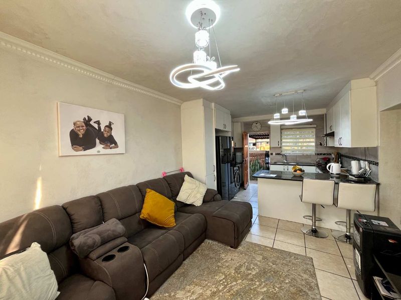 Open-plan living area featuring a functional kitchen with granite countertops, tiled flooring, and modern pendant lighting, seamlessly connected to the lounge space.