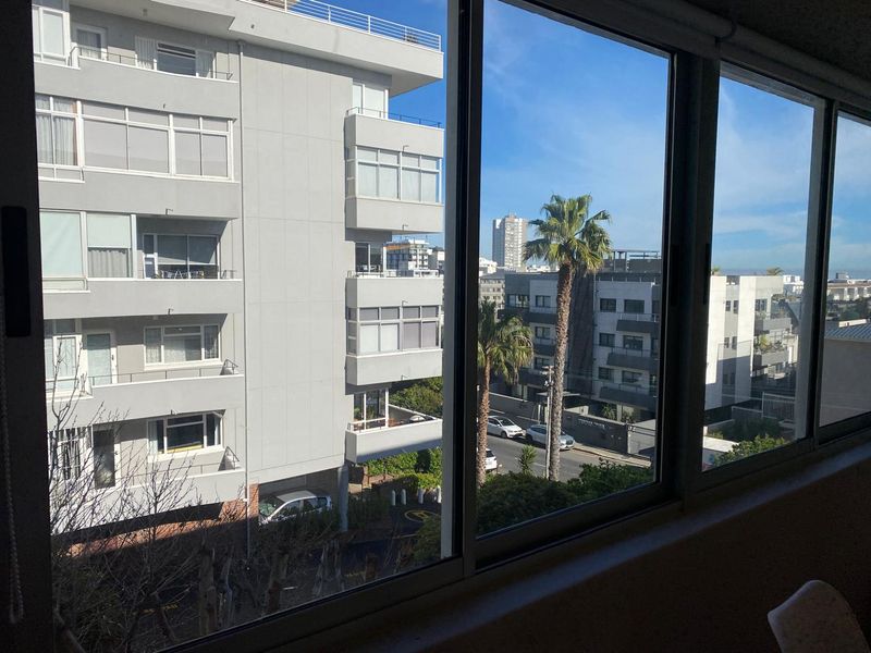 A clear view of the surrounding urban apartment complex and streetscape through a large, multi-pane window.