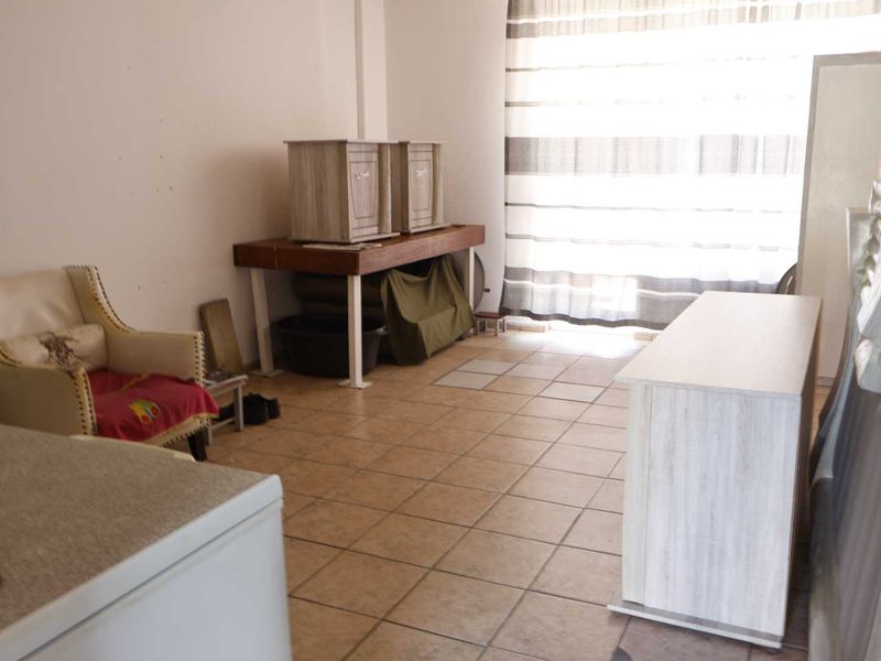 A living area featuring tiled flooring and a large window, currently used for storage with visible wear on the floor tiles.