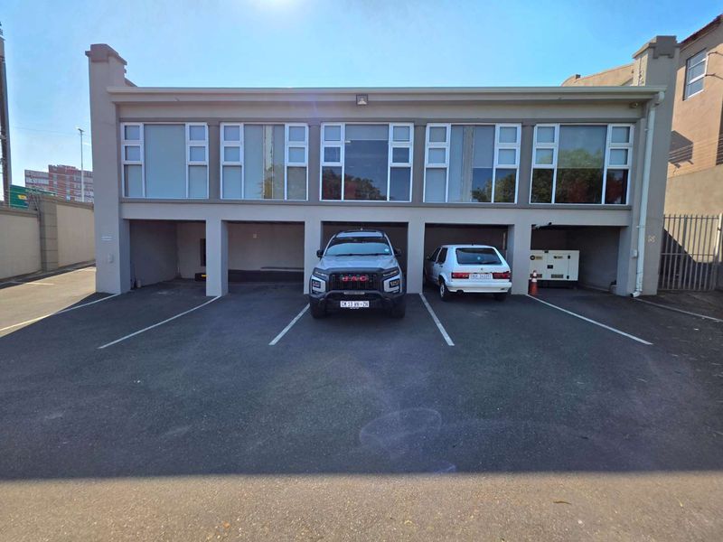 Front elevation of a commercial building featuring covered parking bays on the ground level and large windows on the upper floor.