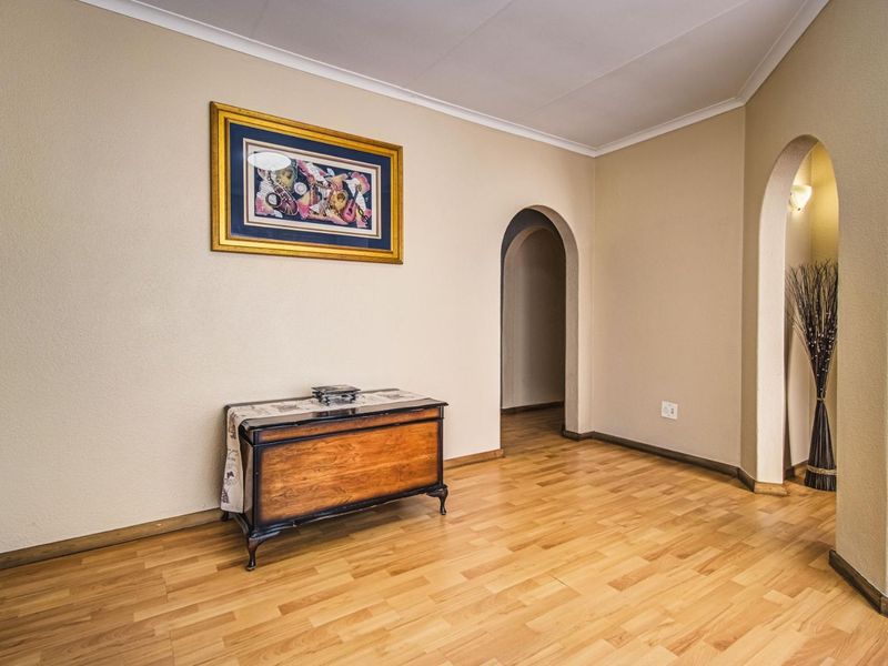 A well-maintained hallway featuring light-toned laminate flooring and distinctive arched doorways leading to adjacent living spaces.