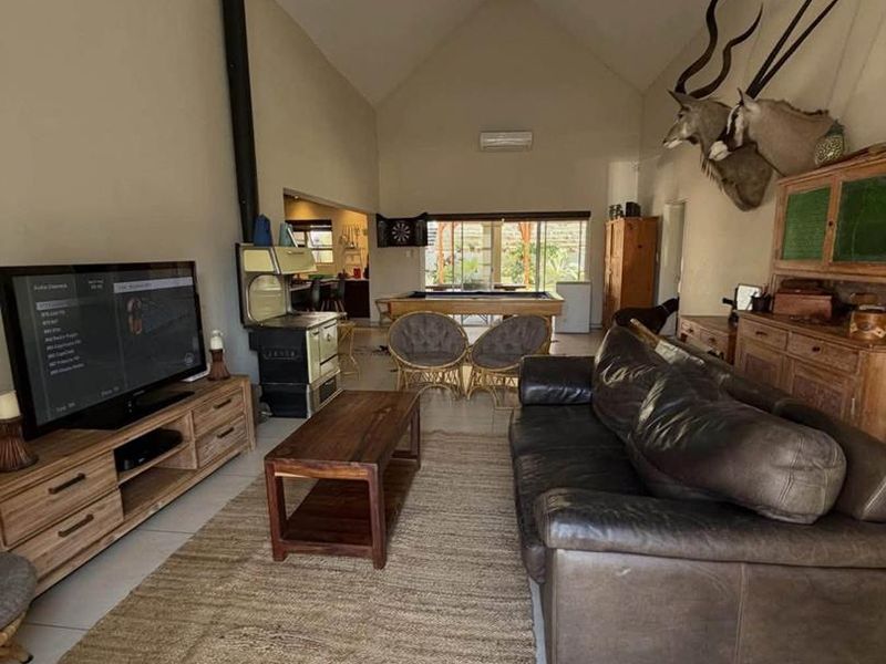 Spacious open-plan living area featuring a vaulted ceiling, tiled floors, and a wood-burning stove, creating a warm and inviting atmosphere.