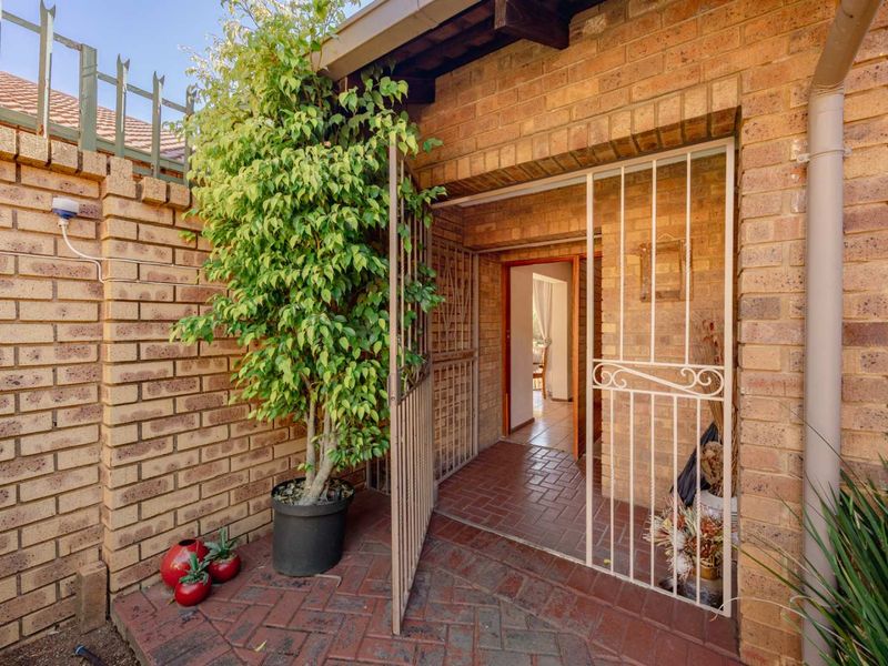 A private rear entrance area featuring facebrick walls, brick paving, and a secure metal gate leading into the home.