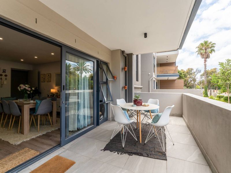 A spacious covered balcony featuring modern tiled flooring, recessed lighting, and large sliding glass doors providing seamless access to the interior living area.