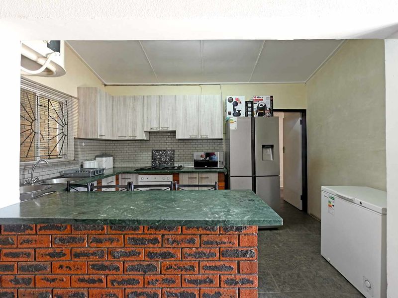Functional kitchen featuring a brick breakfast bar, stone countertops, subway tile backsplash, and ample built-in cabinetry with integrated cooking appliances.
