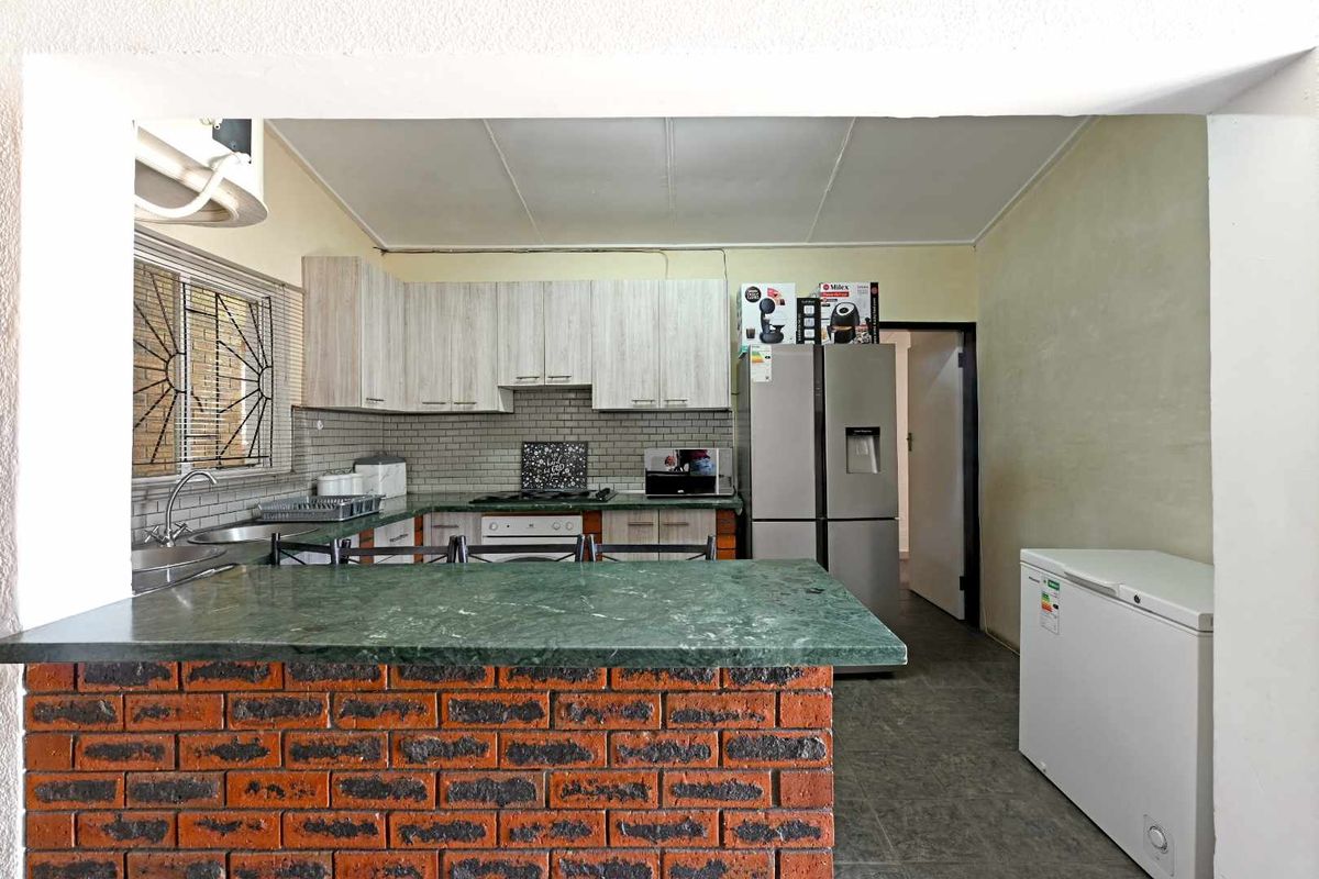 Functional kitchen featuring a brick breakfast bar, stone countertops, subway tile backsplash, and ample built-in cabinetry with integrated cooking appliances.