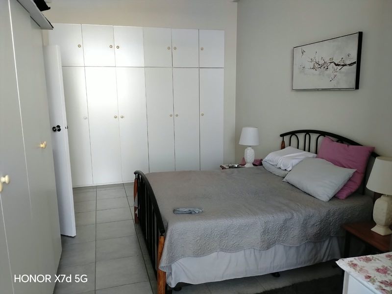 A bedroom featuring neutral walls, tiled flooring, and extensive white built-in cupboards providing ample storage space.