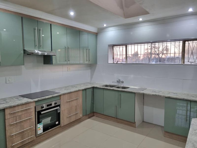 Modern kitchen featuring two-tone cabinetry, stone countertops, integrated oven and hob, double sink, and tiled splashbacks with recessed lighting.