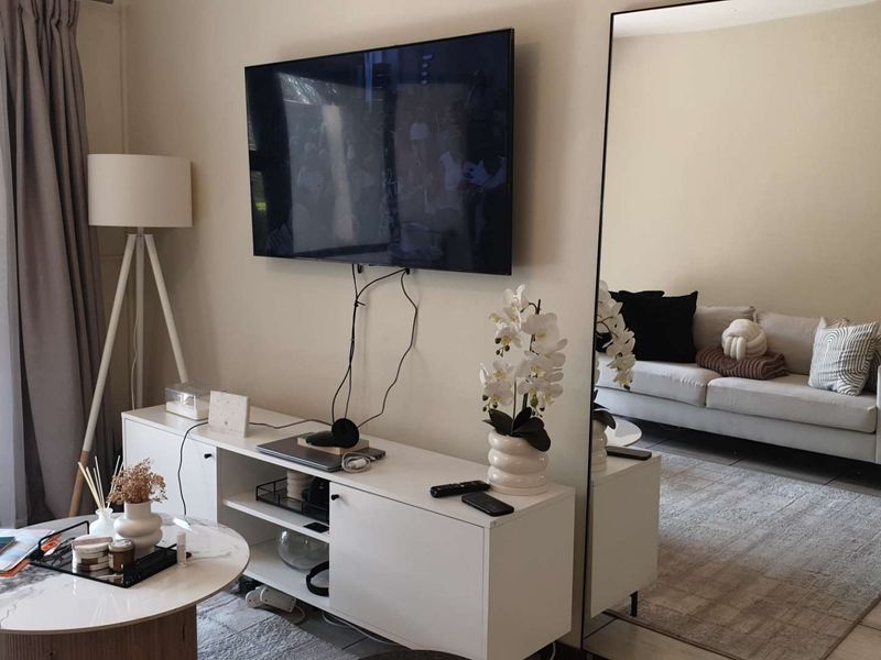 A bright living room featuring tiled flooring and a large sliding glass door providing natural light.