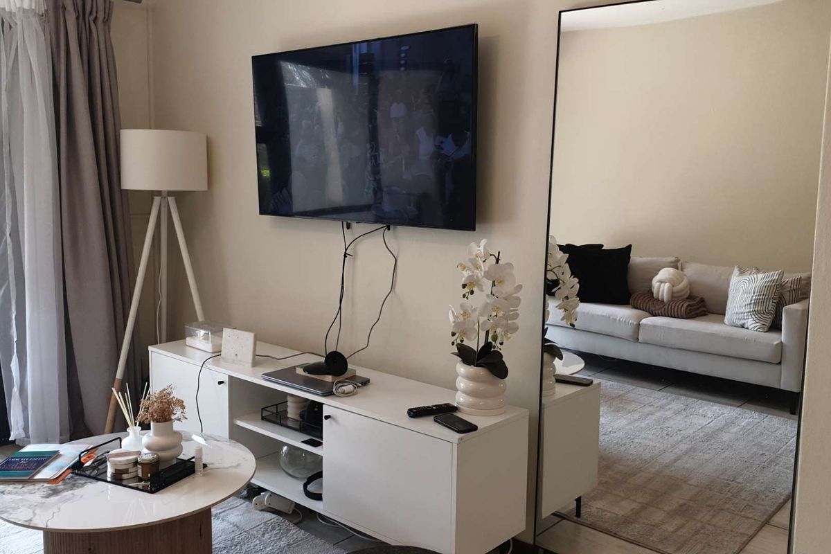 A bright living room featuring tiled flooring and a large sliding glass door providing natural light.