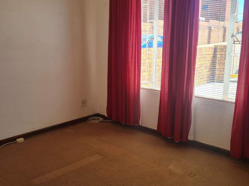 An empty bedroom featuring carpet flooring, window blinds, and natural light, presenting a blank canvas for potential renovation or restyling.