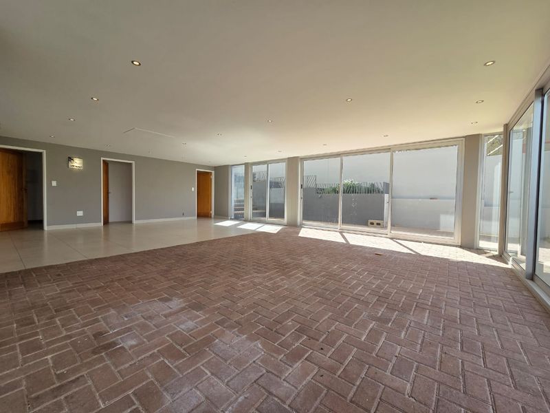 Spacious, empty living area featuring brick paver flooring, recessed lighting, and large sliding glass doors providing ample natural light and access to the exterior.
