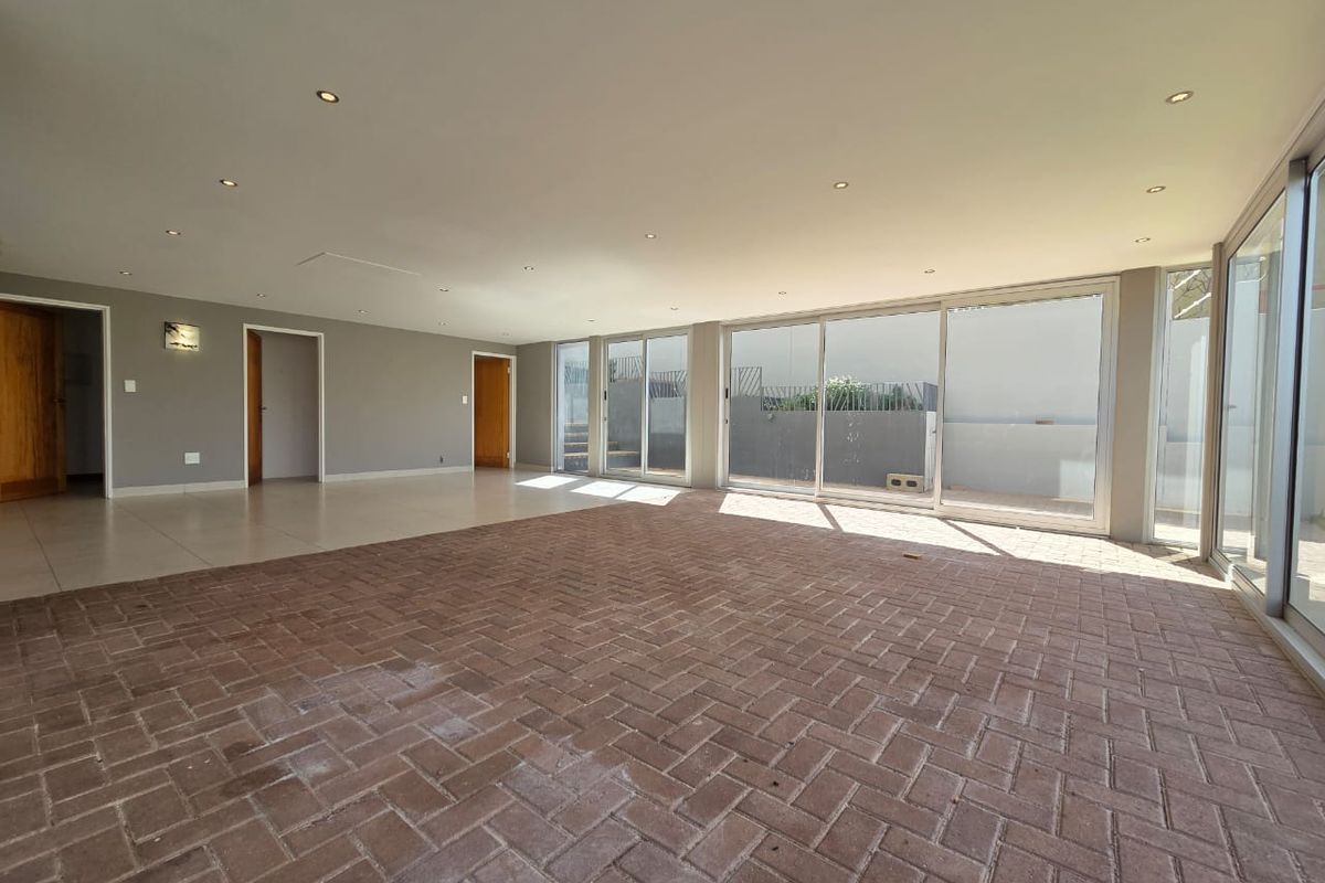 Spacious, empty living area featuring brick paver flooring, recessed lighting, and large sliding glass doors providing ample natural light and access to the exterior.