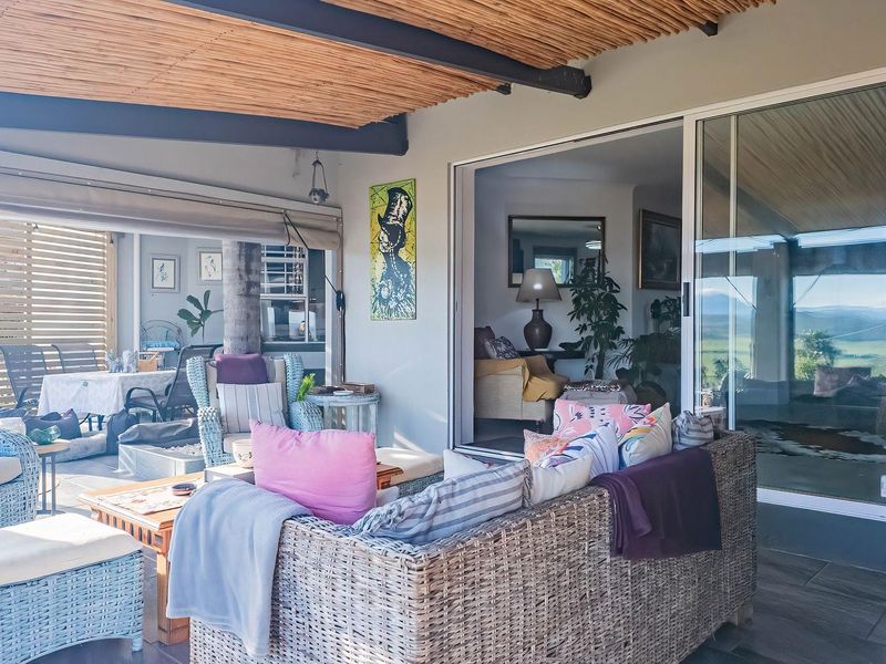 A spacious covered patio featuring a natural thatched roof, tiled flooring, and large sliding glass doors providing seamless indoor-outdoor flow.