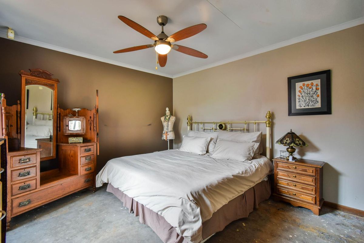 A bedroom featuring a ceiling fan and neutral wall tones, currently requiring flooring installation and cosmetic updates to complete the space.