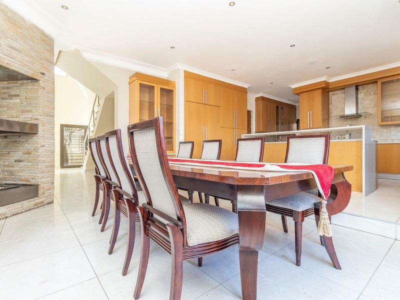 Spacious open-plan dining and kitchen area featuring a stone-clad fireplace, modern cabinetry, and tiled flooring, creating a functional and inviting living space.