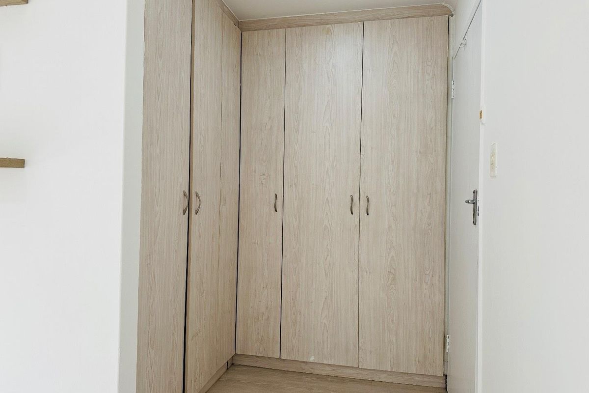 A bedroom featuring light wood-grain built-in cupboards providing ample storage space.