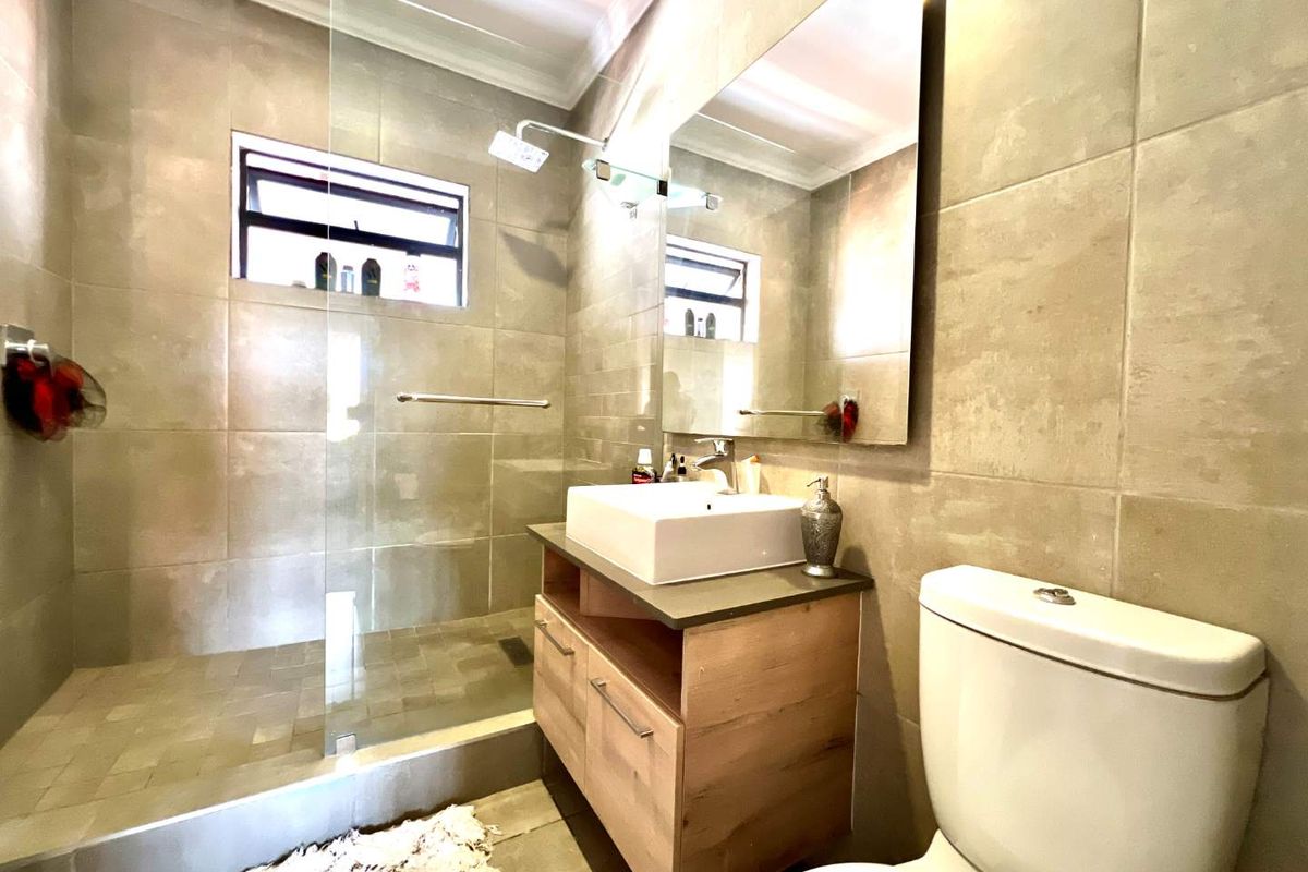 Modern bathroom featuring a walk-in shower with glass screen, floating vanity with basin, and wall-mounted mirror.