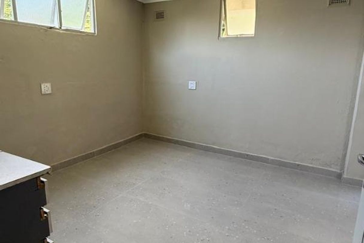 A bright, empty bedroom featuring neutral wall tones, polished tiled flooring, and multiple windows providing natural light.