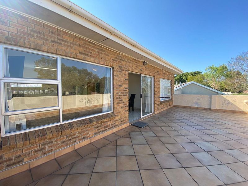 Spacious outdoor balcony featuring tiled flooring, brick exterior walls, and large sliding glass doors providing access to the interior living space.