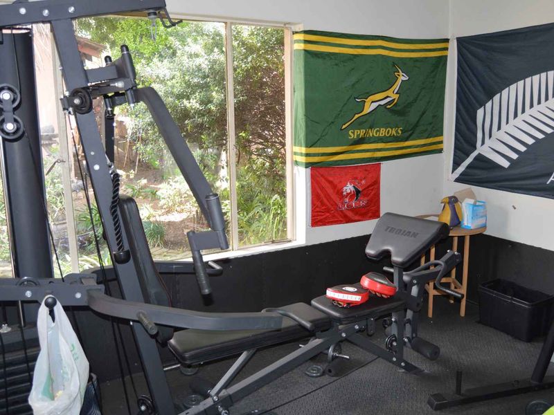 A dedicated home gym space featuring a large window overlooking the garden area.
