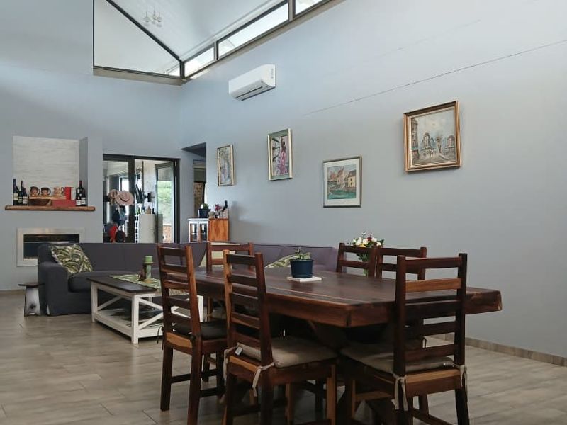Spacious open-plan living and dining area featuring high vaulted ceilings, clerestory windows, modern tiled flooring, and a built-in fireplace.