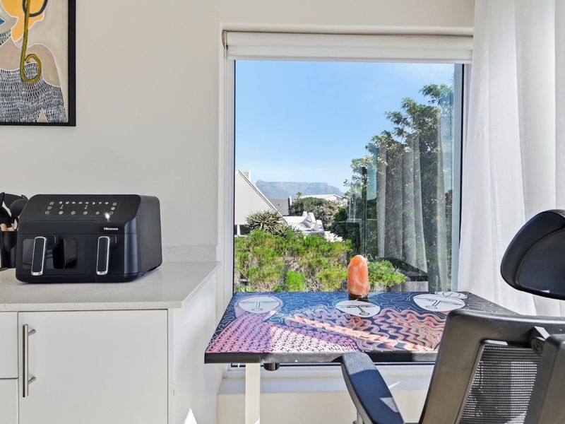 A bright kitchen area featuring white cabinetry, quartz countertops, and a large window offering a scenic outdoor view.