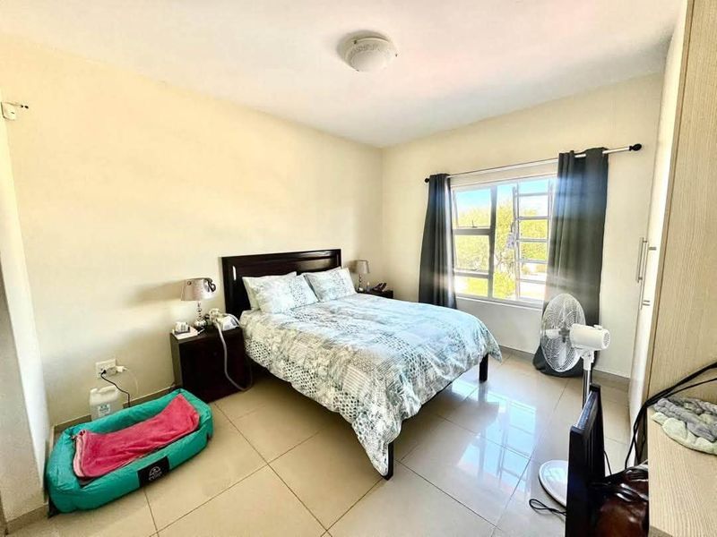 A functional bedroom featuring tiled flooring, a built-in wardrobe, and natural light from the window.