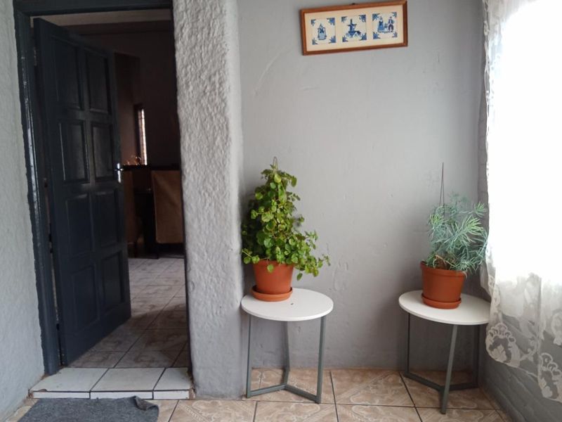 An entry area featuring tiled flooring, textured grey walls, and a dark panelled door leading into the home.