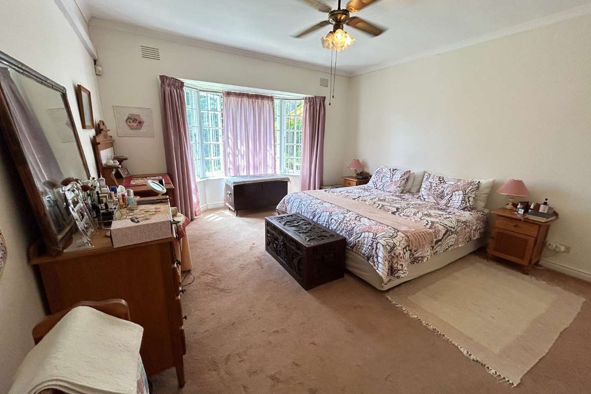 Spacious bedroom featuring a large bay window, ceiling fan, and neutral wall finishes, offering a comfortable and well-lit living space.