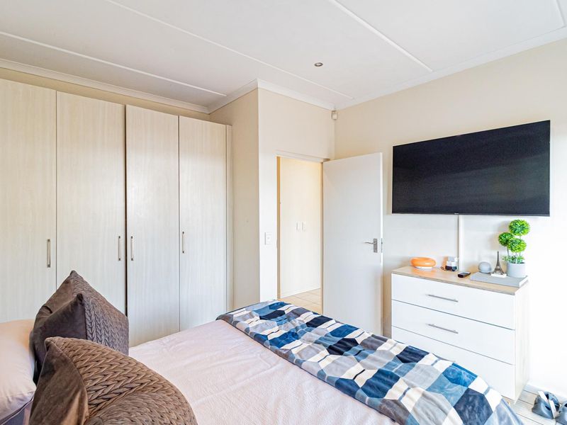 A well-maintained bedroom featuring neutral walls, light wood-finish built-in cupboards, and recessed ceiling lighting.