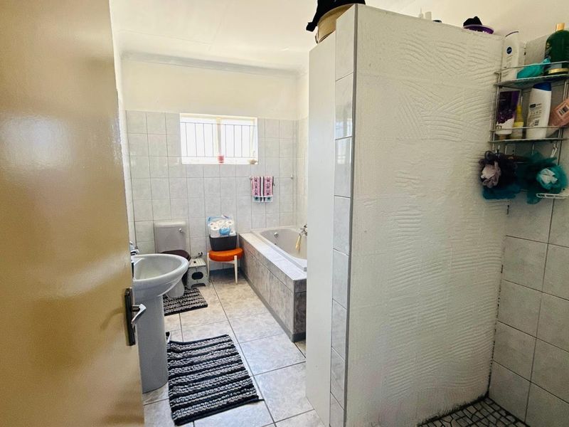 A functional bathroom featuring a pedestal basin, toilet, built-in bathtub, and a separate shower enclosure with tiled finishes throughout.