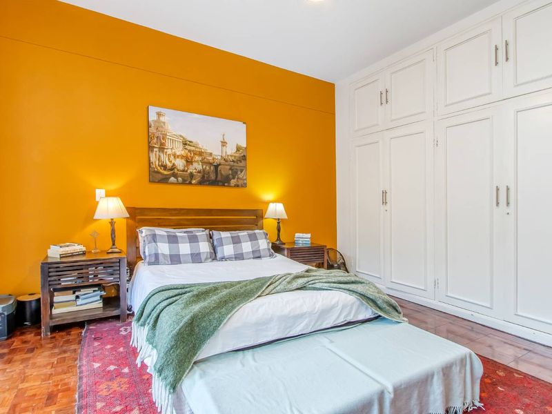 A well-maintained bedroom featuring classic parquet flooring and extensive floor-to-ceiling built-in cupboards for ample storage.