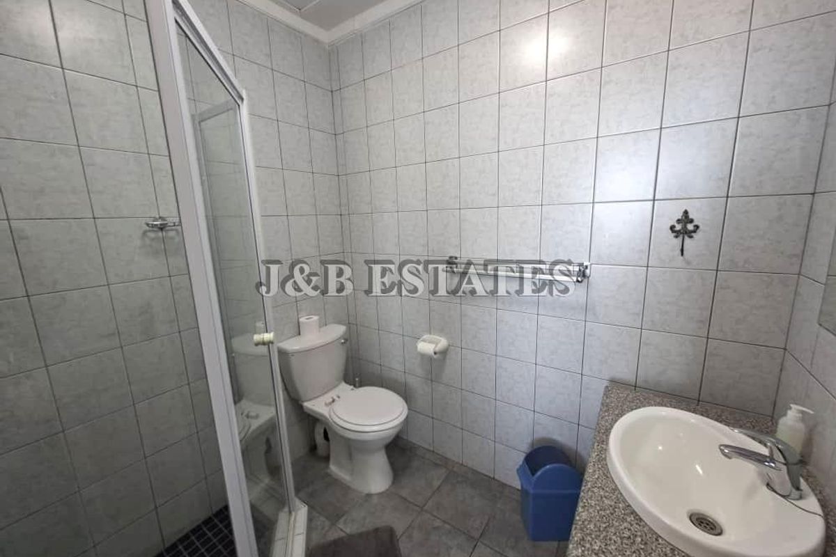 A functional bathroom featuring a glass-enclosed shower, a standard toilet, and a vanity with a basin and stone-look countertop.