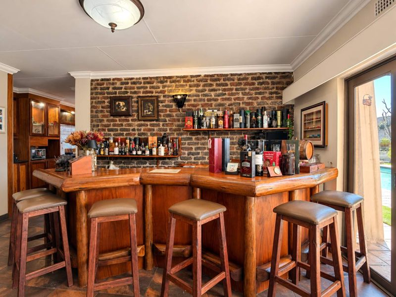 A dedicated bar area featuring a rustic wooden counter, exposed brick feature wall, and direct access to the outdoor pool area via sliding doors.