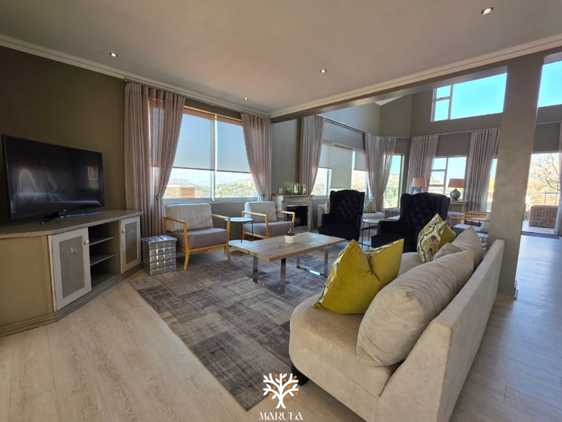 Spacious living room featuring double volume ceilings, large windows with natural light, laminate flooring, and a built-in fireplace.
