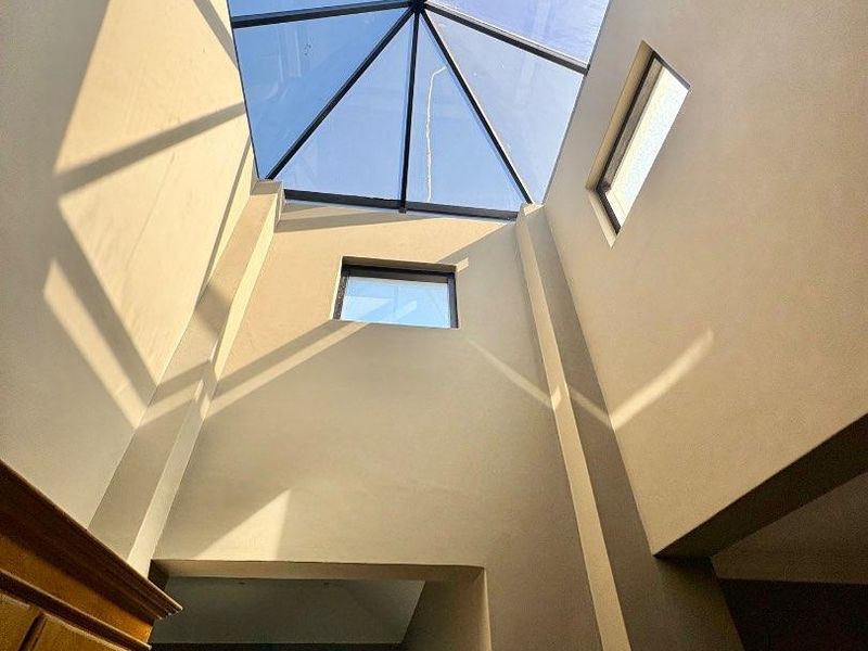 A bright and airy entrance hall featuring a large architectural skylight that floods the space with natural light.
