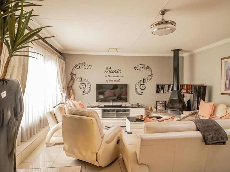 Spacious living room featuring a modern freestanding fireplace, tiled flooring, and a ceiling fan, offering a comfortable and inviting atmosphere.