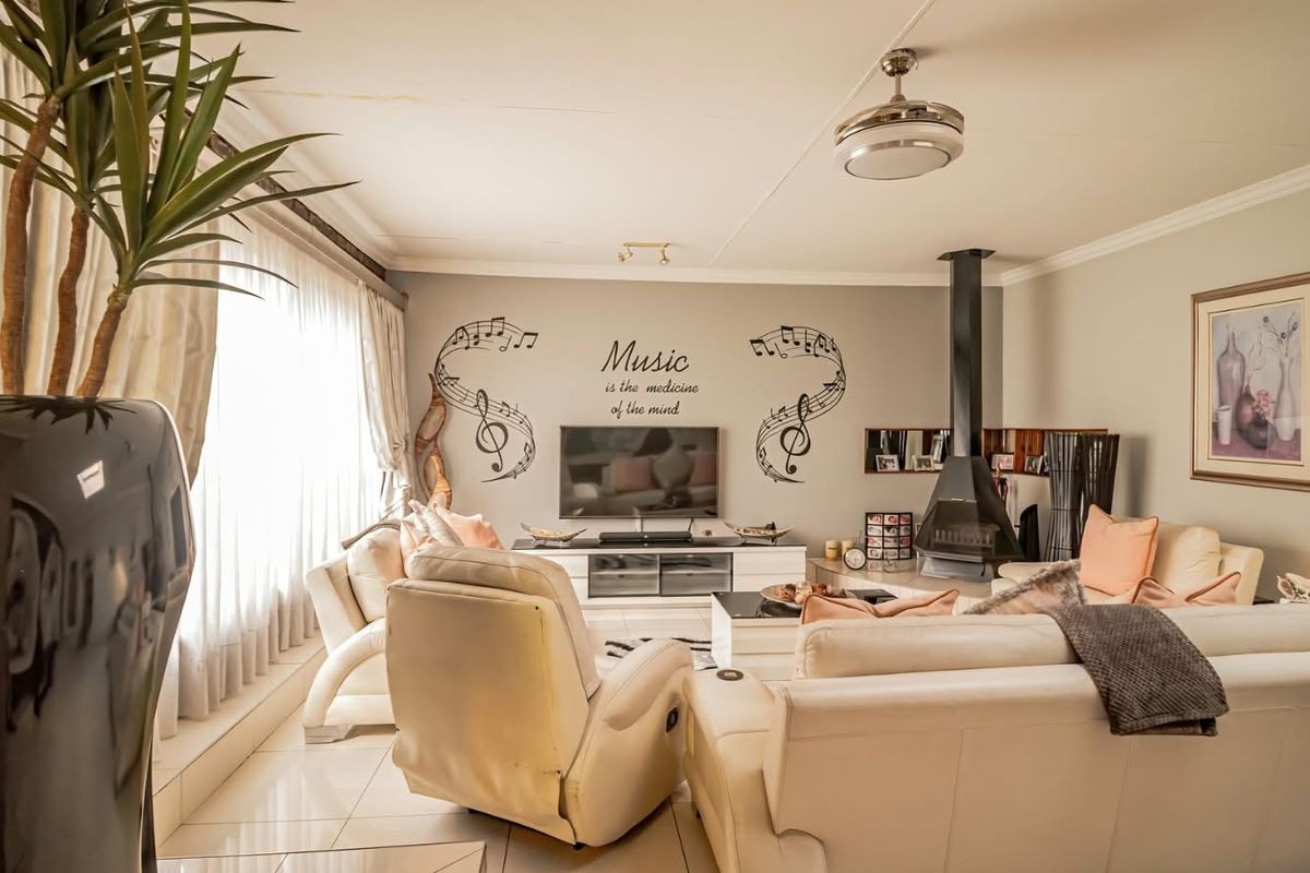 Spacious living room featuring a modern freestanding fireplace, tiled flooring, and a ceiling fan, offering a comfortable and inviting atmosphere.