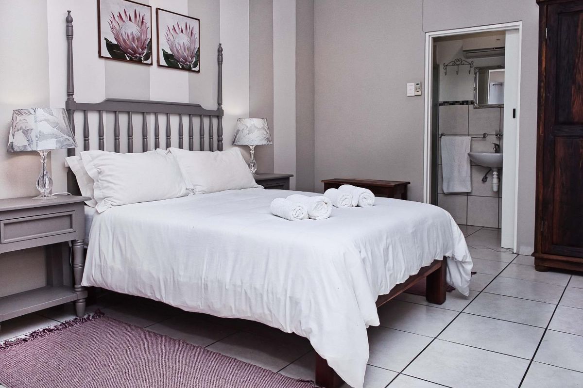 A well-maintained bedroom featuring tiled flooring and an en-suite bathroom with a pedestal basin.