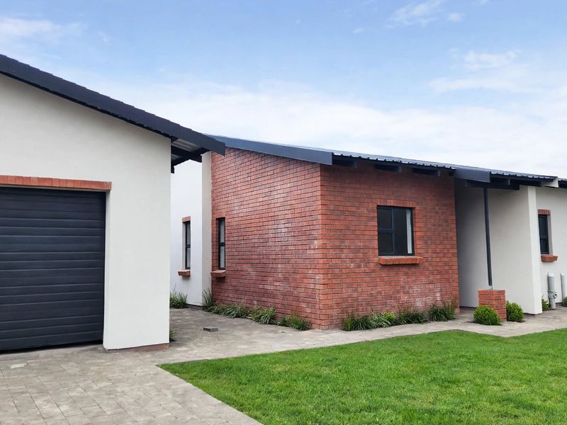 Modern single-story home featuring a combination of brick and plastered exterior finishes, a paved driveway, and a secure garage.