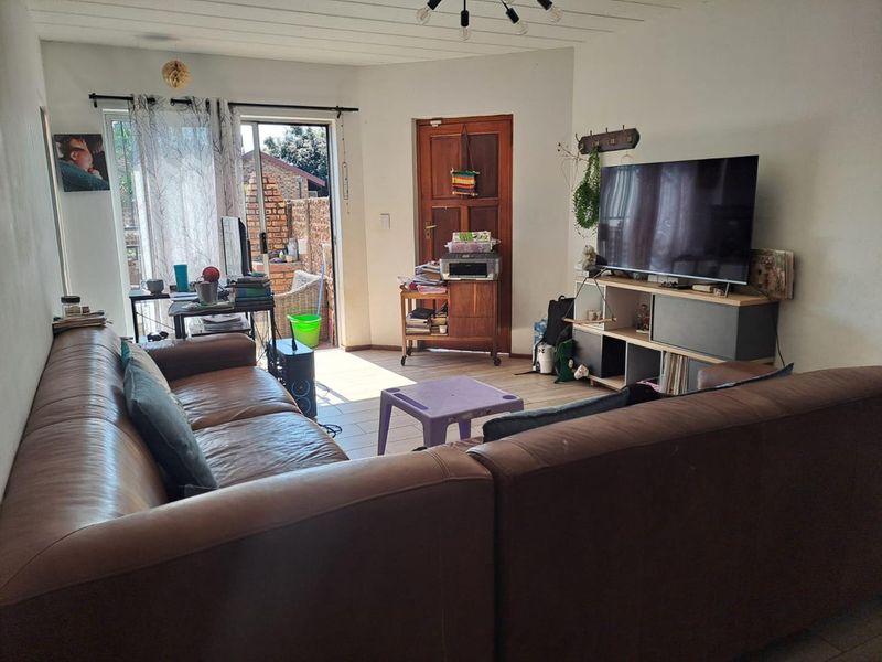 A living room featuring tiled flooring and a sliding glass door providing access to an outdoor area.
