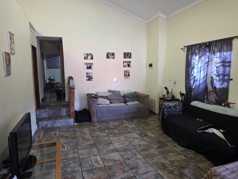 A living room featuring tiled flooring and a vaulted ceiling, with a staircase leading to an adjacent area.