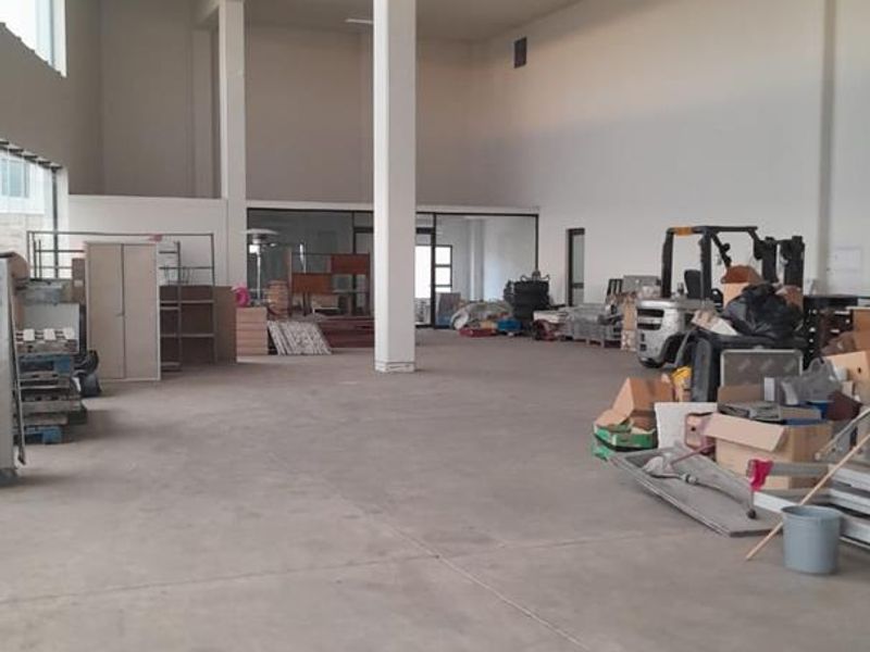 Spacious industrial utility area featuring high ceilings, concrete flooring, and structural columns, suitable for various commercial or storage applications.